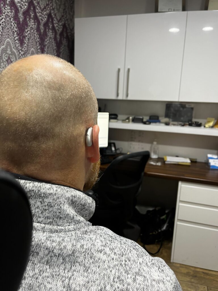 Mr Dean Williams photo from back highlighting his hearing aids.