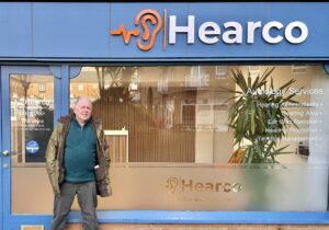 Mr Oliver St John in front of Hear Co Clinic getting his hearing back.